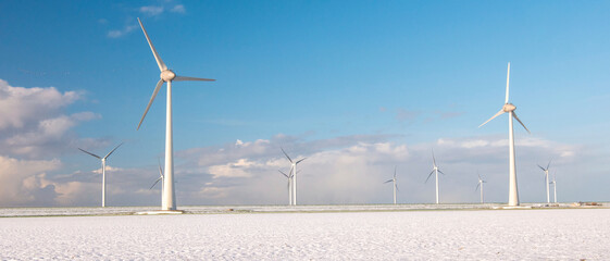 Windmill turbines n the Netherlands during winter with snow at the meadow field, windmill park...