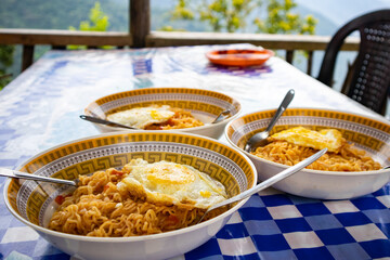 Noodles and omelette served in bowls for breakfast on a table. 