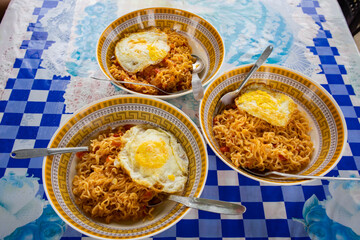 Noodles and omelette served in bowls for breakfast on a table.