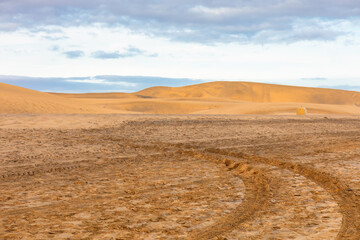 Undulating dunes creating an otherworldly landscape . Tracks imprinted by the passage of transport vehicles or machines at desert landscape