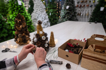 Elderly caucasian woman making cones decoration for christmas.