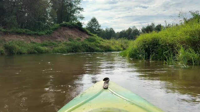 Kayaking on a river in Summer. Kayak's boat bow. Focus on beautiful scenery river with calm water route along green forest. No people. Watersport and recreational activity concept.