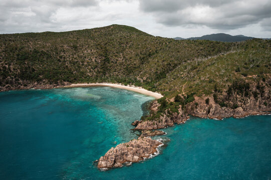 Aerial view of Blue Pearl Bay with turquoise water and green hills, Hayman Island, Australia.