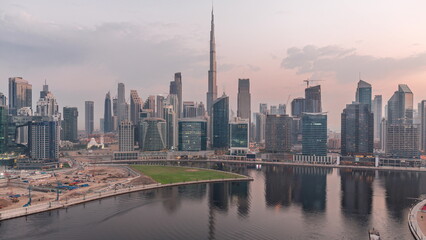 Aerial view to Dubai Business Bay and Downtown with the various skyscrapers and towers night to day...