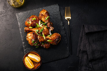 Chicken drumsticks with sesame seeds, Asian cooked chicken on a black background top view - obrazy, fototapety, plakaty