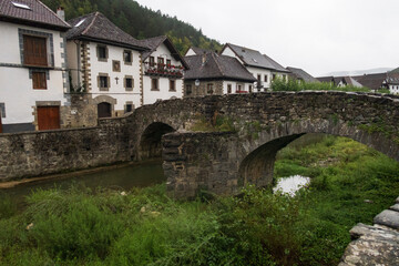 Fototapeta na wymiar Vista del pueblo Ochagavía y sus casas típicas desde el puente de piedra medieval, selva de Irati, Navarra, España.