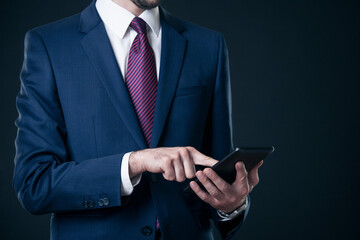 Close up shot of businessman in suit using tablet pc