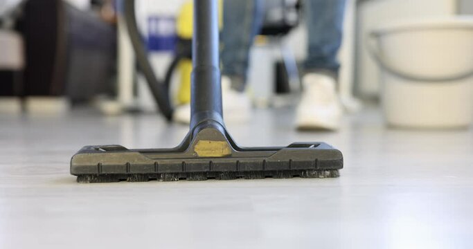 Employee of cleaning company vacuums floor in office. Room cleaning concept