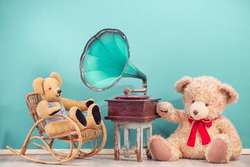 Teddy Bear toys sitting near vintage gramophone phonograph front mint blue background. Nostalgic...