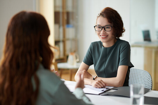 Cheerful HR manager talking to applicant in meeting