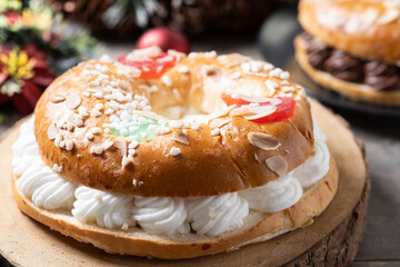 Individual Epiphany cake roscon de reyes with cream on wooden table. Close up