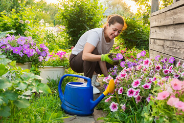 Gardening and agriculture concept. Young woman farm worker gardening flowers in garden. Gardener...