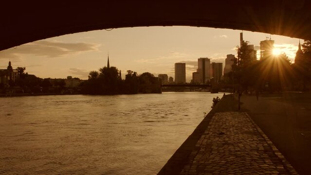 Wide angle sunset silhouette of the Frankfurt Skyline framed by Ignatz Bubis Bridge. Summer evening with people walking 