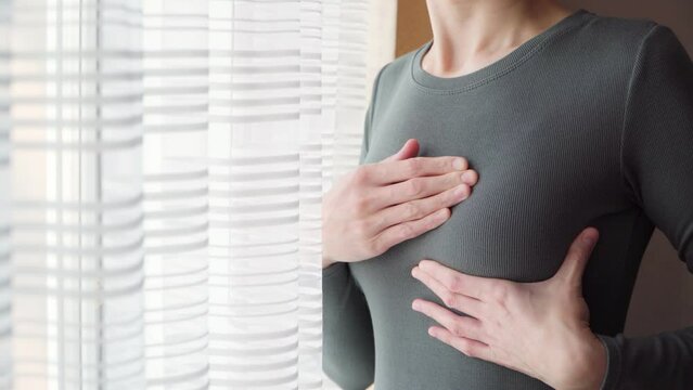 A young woman checks her breasts for tumors and oncology. Self-examination to avoid breast cancer.