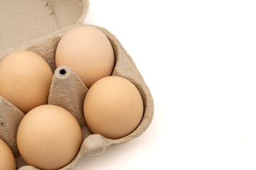 Chicken eggs on a cardboard egg box, isolated on white background with copy space. Close-up view.