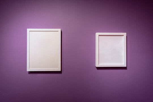 Blank white color picture frame template for place image or text inside on the colorful purple wall.
