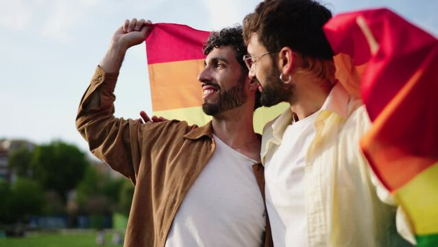 Gay couple joyously holding up pride flag, their faces alight with smiles, symbolizing spirit of freedom and equality. Homosexual happy men proudly celebrating their love and LGBTQ+ rights