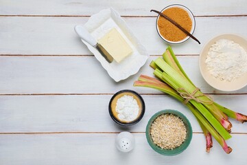 Prepared ingredients for cooking rhubarb crumble on a light wooden background. Rhubarb recipes.