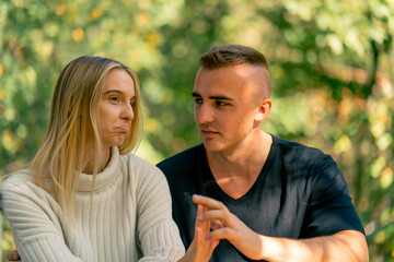 Obraz premium A young couple a guy and a girl are talking seriously while sitting together on sunny day in nature