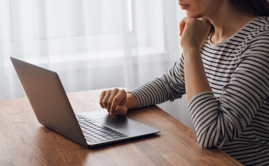 A close-up of a woman's hands typing on a laptop keyboard. Working online on a wooden desk. Ideas for working on the Internet
