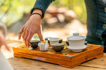 Fototapeta na wymiar Close-up shot of a tea master's male hand placing a bowl on chahai for a traditional tea ceremony