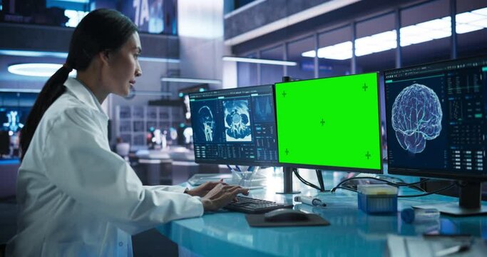 Hospital Research Laboratory: Asian Female Medical Scientist Using Computer Green Screen Chromakey On Display. Neurologist Analysing CT Scans, Finding Treatment for Patients With Brain Damage.