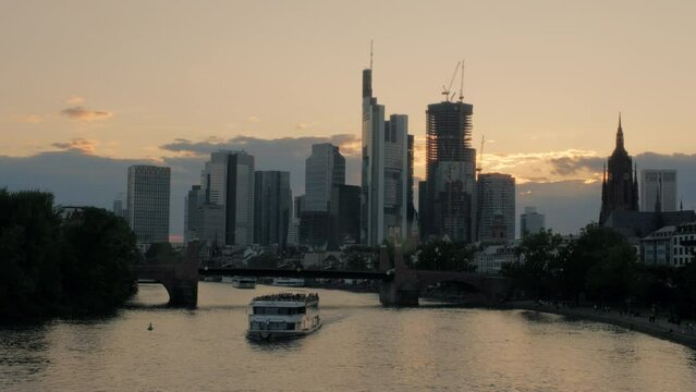 Frankfurt skyline and River Main at sunset from Ignatz Bubis Bridge. A tour boat passes along the river