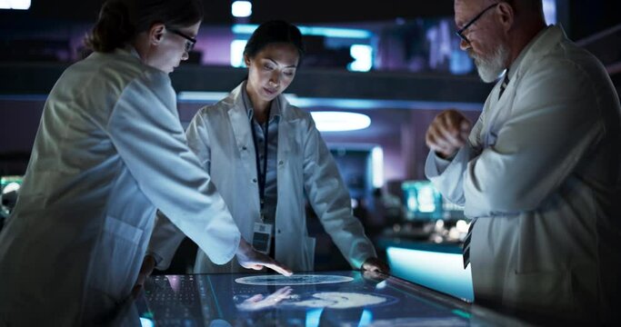 Modern Hospital Medical Cancer Research Center: Diverse Scientists Gathered Around Interactive Touch Screen Table With CT Scans Of Brain On Display. Three Doctors Discussing Brain Tumor Treatment.