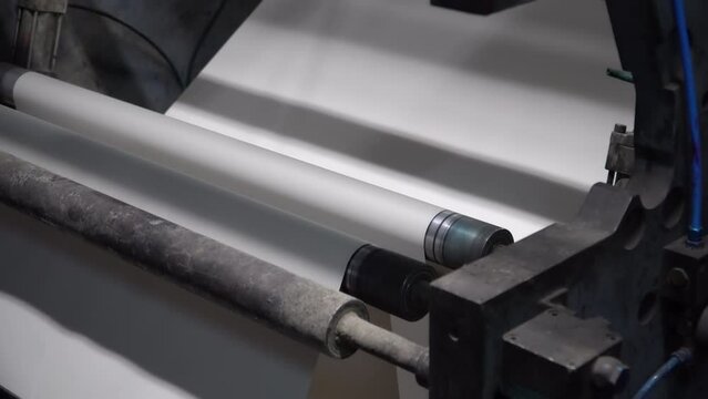 Close up view of a paper running through the printing machine during newspaper printing process in a real time.