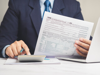 Hand holding of form 1040. U.S. individual income tax return while sitting at the table in the office
