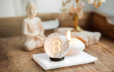 Number eight on Gemstone sphere or crystal balls known as crystallum orbis and orbuculum. Natural clear quartz ball on stand on wood tray in home. Predictions concept.