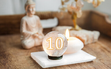 Number ten on Gemstone sphere or crystal balls known as crystallum orbis and orbuculum. Natural clear quartz ball on stand on wood tray in home. Predictions concept.