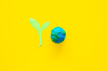 Clay globe planet Earth with paper green plant. Safe our planet concept