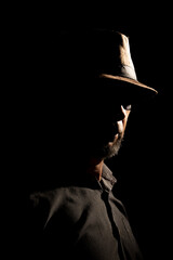 Discreet portrait of detective man with hat in darkness.