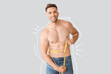 Muscled young man after weight loss with measuring tape on light background