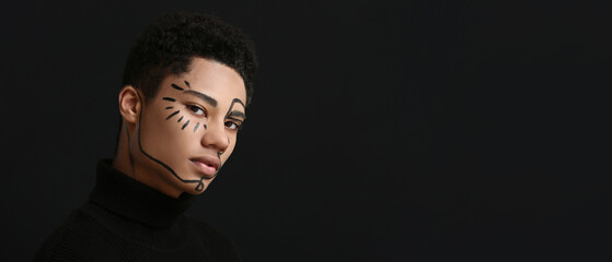 Young African-American guy with painted face on dark background with space for text