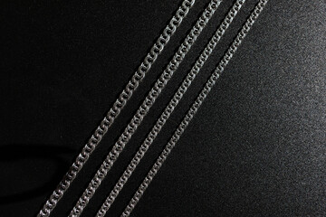 Different silver chains on black background, different sizes, subject photography