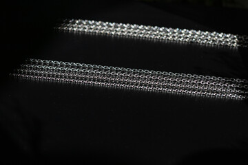 Different silver chains on black background, different sizes, subject photography