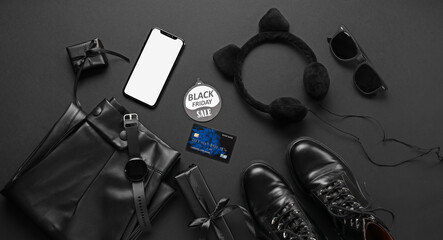 Accessories with stylish female clothes and mobile phone on dark background. Black Friday sale