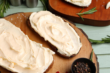 Board of tasty sandwiches with cream cheese on green wooden background