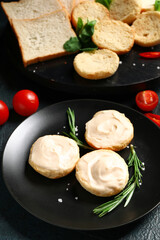 Plate of tasty croutons with cream cheese on dark background
