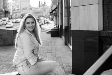 Smiling European plus size model in casual clothes, city behind her. Pretty nice chubby woman