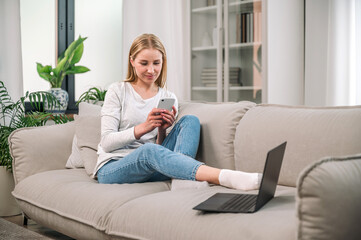 Woman sitting on sofa and working online at home