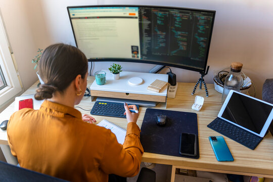 Computer programmer working from home. Teleworking concept. Business woman taking notes.