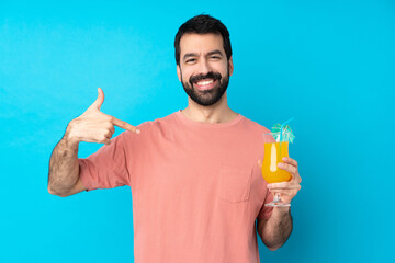 Young man over holding a cocktail over isolated blue background proud and self-satisfied