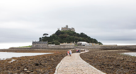 A walkway seen at low tide leading to a fortress on an island.