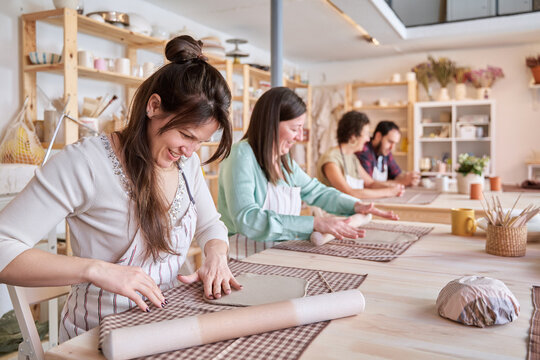 Group of people having fun while working with ceramic in a pottery workshop. Craft and hobby concept.