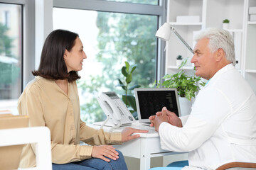 Senior doctor talking with female patient in medical office