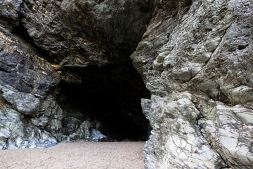 A large and dark cave located on the shores of Tintagel in Cornwall.