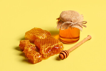 Jar of sweet honey and combs on yellow background